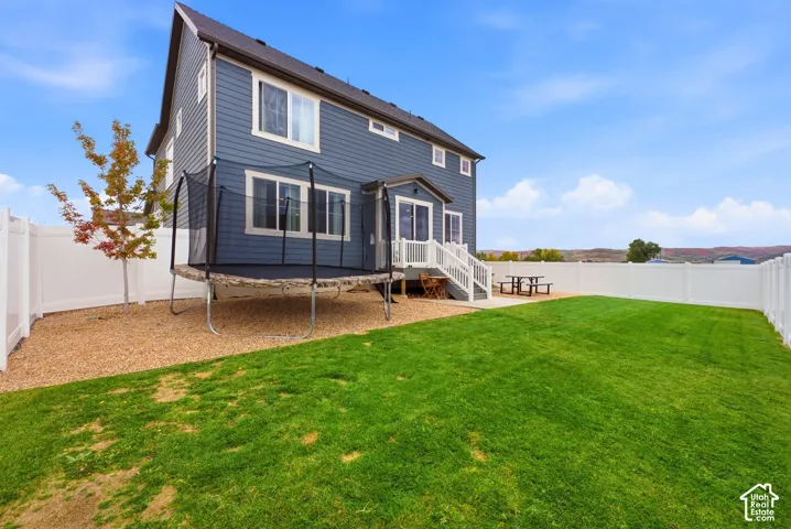 Expansive fenced backyard featuring a manicured lawn, gravel landscaping, and a two-story exterior with siding