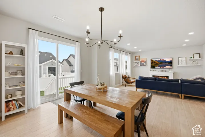 Open concept living space featuring light wood-finish flooring, a fireplace with a white mantel, and recessed lighting
