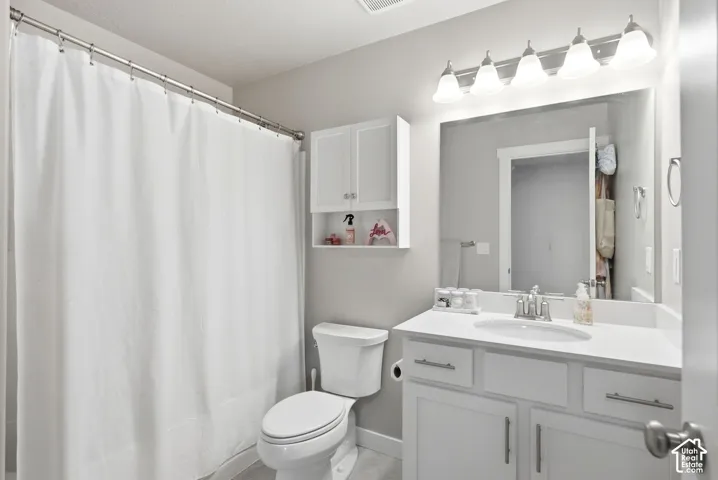 Vanity with a single basin sink, wall-mounted mirror, and white shaker-style cabinetry