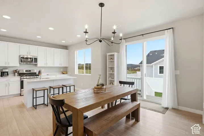 Light wood-finish flooring, white cabinetry, stainless steel appliances, white countertops, and a sliding glass door to exterior