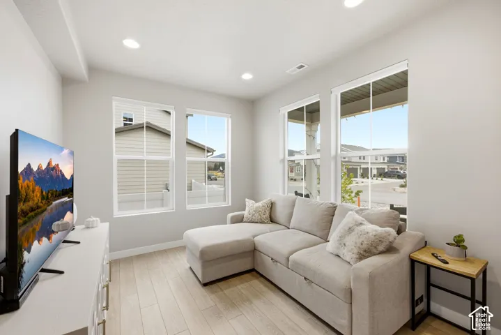 Recessed lighting, wood-finish flooring, white walls, multiple windows, and a built-in media cabinet