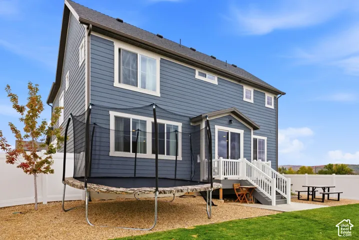 Blue exterior siding with white trim, a gabled roof, and a white privacy fence