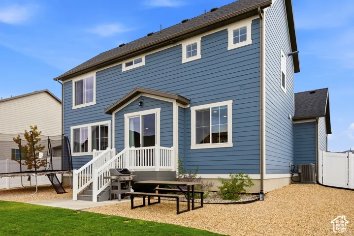 Two-story exterior with blue siding, white trim windows, a white deck with railings, and a concrete patio