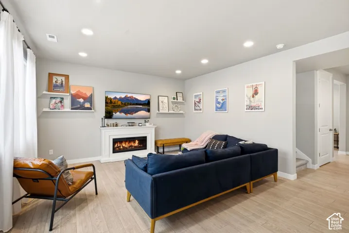 Recessed lighting, light wood-finish flooring, white fireplace, and white trim