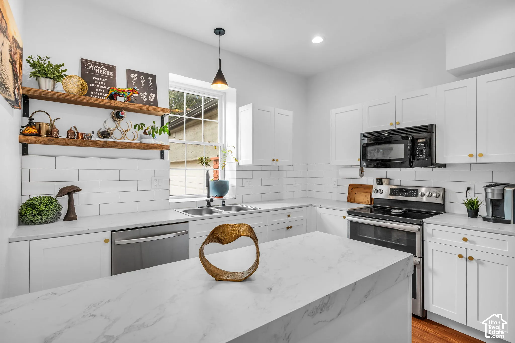 Bright kitchen featuring white shaker cabinetry, stainless steel appliances, white subway tile backsplash, light stone-finish countertops, and wood-finish flooring