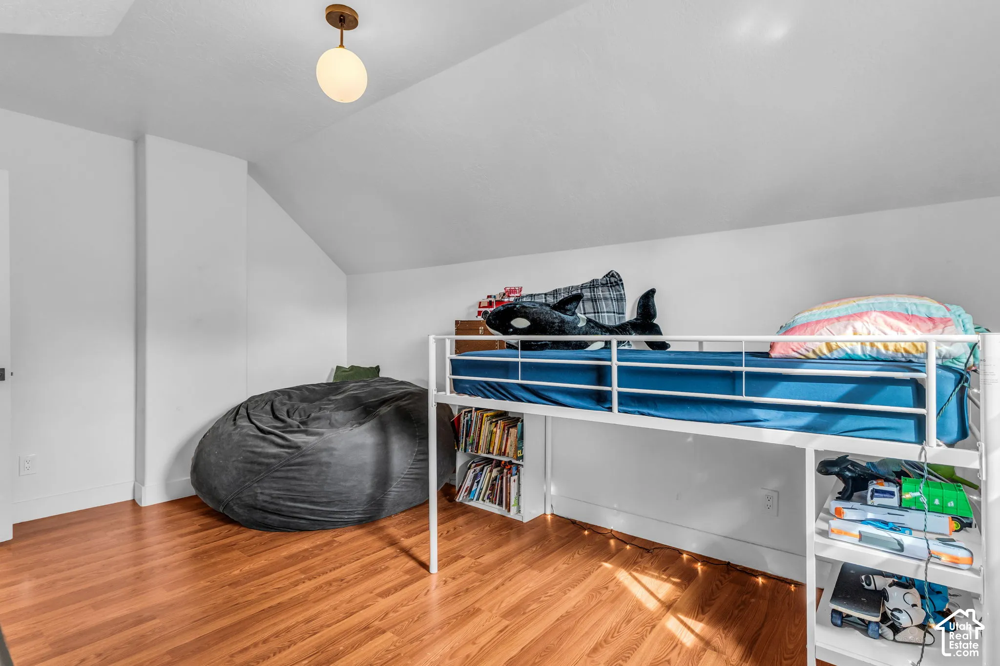 Wood-finish flooring, white walls, and a prominent built-in loft bed frame with integrated shelving