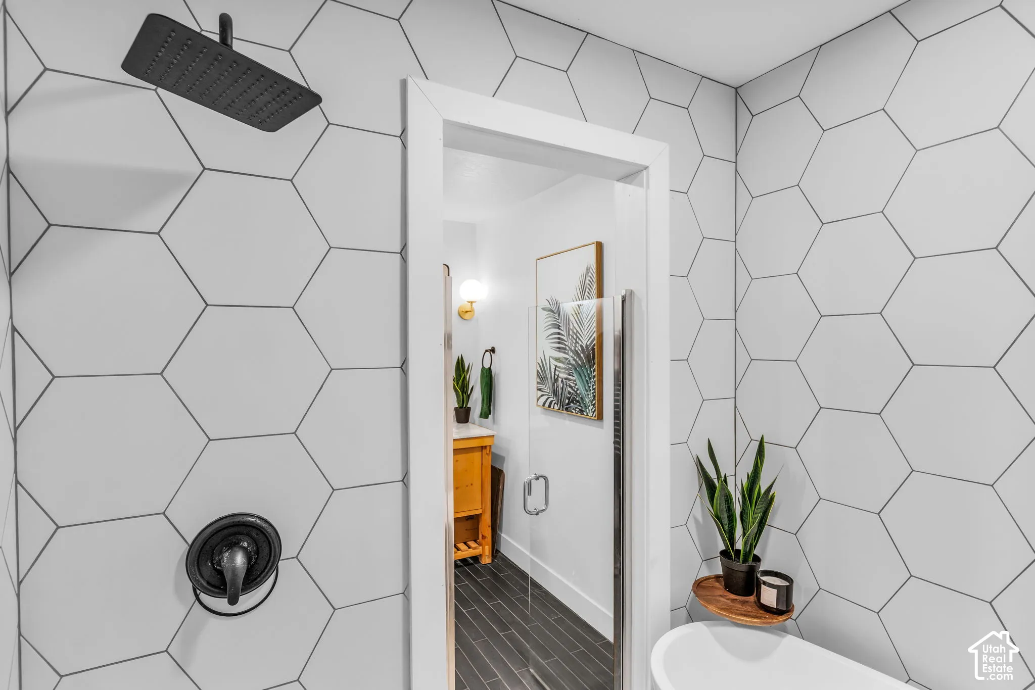 Shower with matte black rainfall showerhead, coordinating fixture, and white hexagonal wall tiling