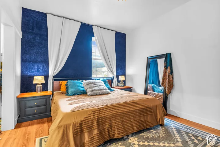 Accent wall with textured blue finish, natural wood-finish flooring, and white window treatments