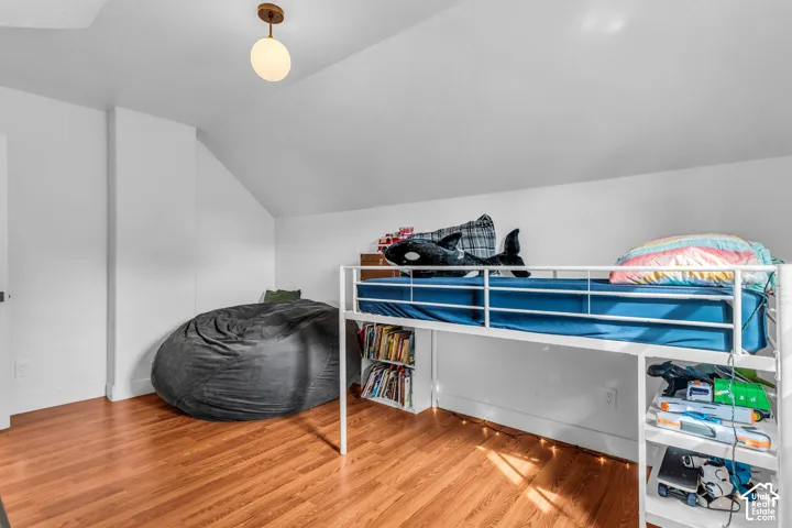 Wood-finish flooring, white walls, and a prominent built-in loft bed frame with integrated shelving