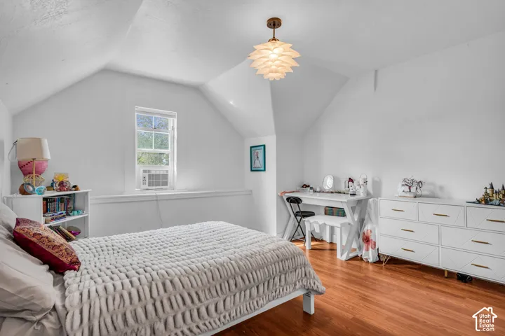Vaulted ceiling, single window, wood-finish flooring, mounted light fixture, white walls