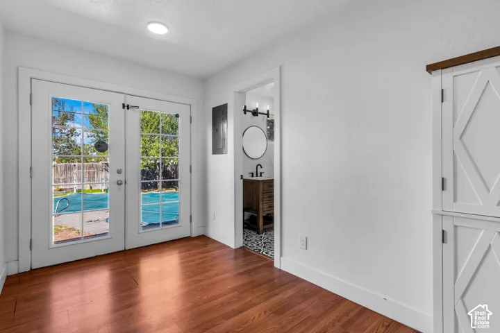 Wood-finish flooring, white walls, double French doors, and built-in cabinetry with a wood top