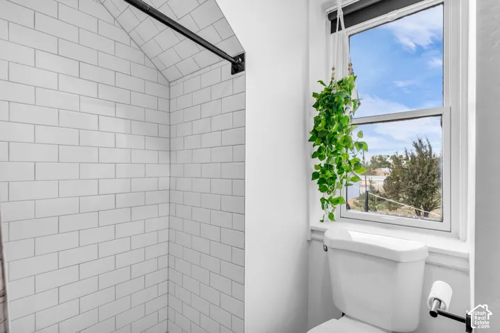 White subway tile shower enclosure with an arched ceiling and a matte black shower rod