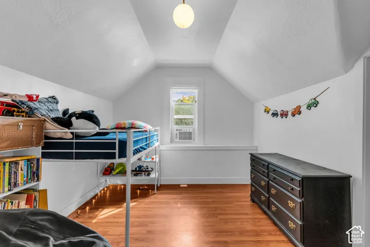 Sloped ceiling architecture with recessed window, wood-finish flooring, and a flush mount ceiling light fixture
