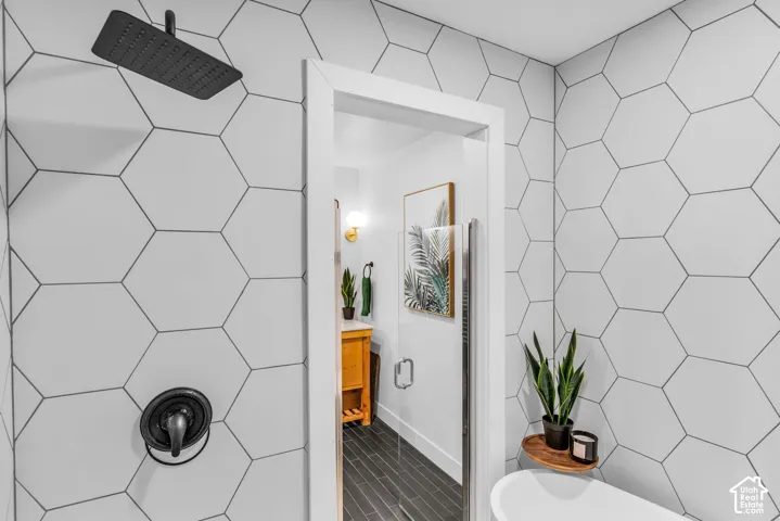 Shower with matte black rainfall showerhead, coordinating fixture, and white hexagonal wall tiling