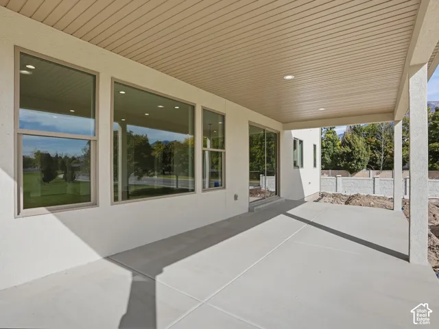 Covered concrete patio with recessed lighting, multiple large windows, and a sliding glass door