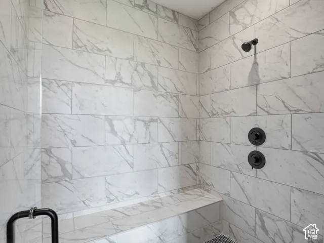 Shower with white stone-look tile, integrated bench, and matte black fixtures