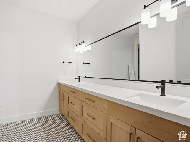 Dual vanity with integrated sinks, light wood-finish cabinetry, matte black fixtures, and a full-width mirror