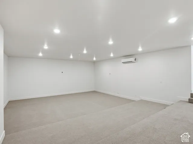 Recessed ceiling lighting, wall-mounted climate control unit, and neutral carpet flooring