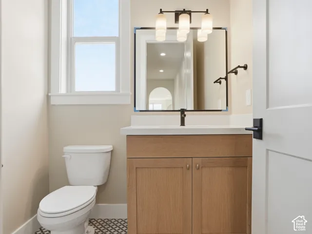 Powder room featuring a single vanity with wood-finish cabinetry, a white countertop, and a black framed mirror with integrated lighting