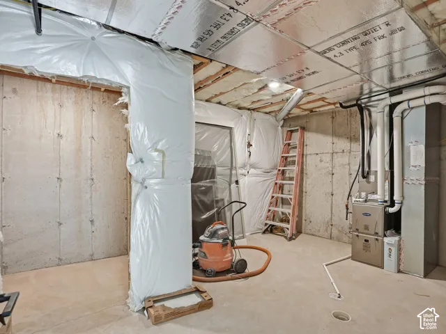 Concrete walls and flooring, exposed ceiling joists with insulation, and visible utility systems