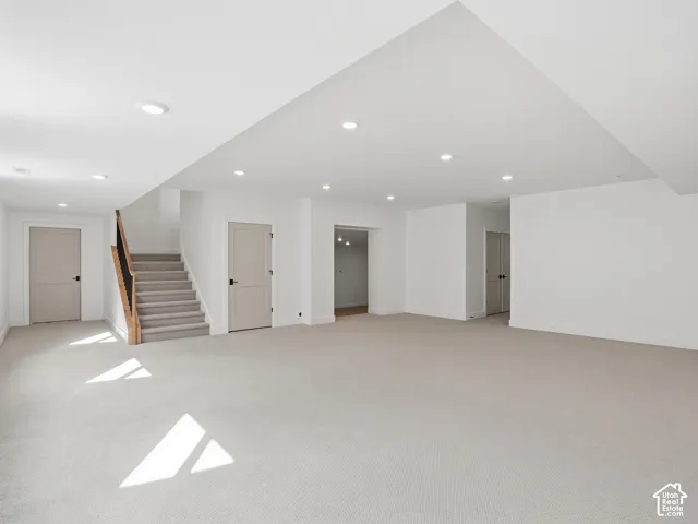 Expansive open-concept room featuring neutral carpet flooring, recessed lighting, and light-colored interior doors