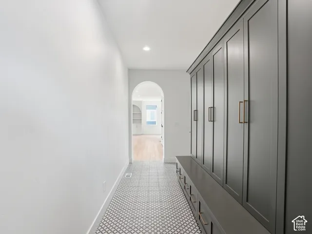 Hallway featuring patterned floor tile, recessed ceiling lighting, a built-in storage bench, and tall built-in cabinetry with bronze-tone hardware