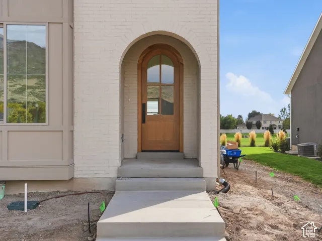 Arched wood entry door with vertical glass panels, set within a brick facade with a complementary bay window