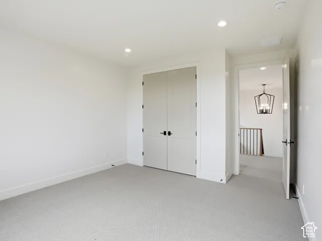 Light gray carpeting, recessed lighting, and white walls