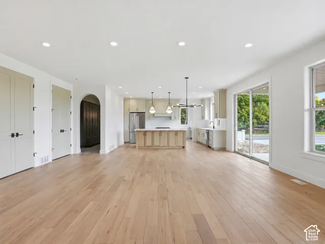 Expansive open-concept living space with light wood-finish flooring, recessed lighting, and a modern kitchen