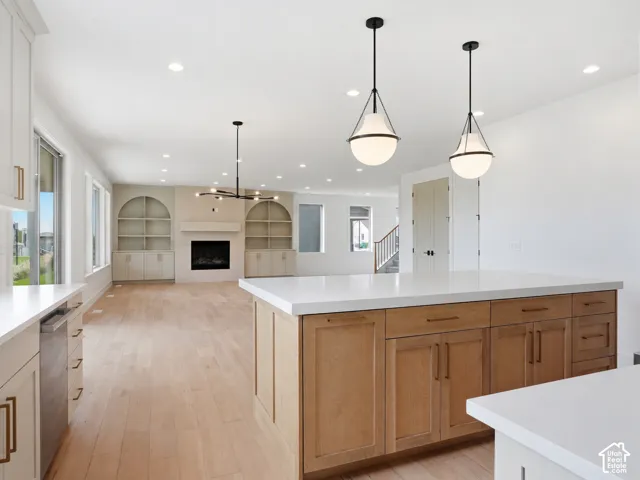 Spacious kitchen island with white countertop, complementing light wood-finish cabinetry, and contemporary pendant lighting