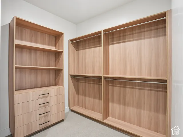 Custom closet system with wood-finish shelving, integrated drawers featuring matte black pulls, and multiple clothing rods