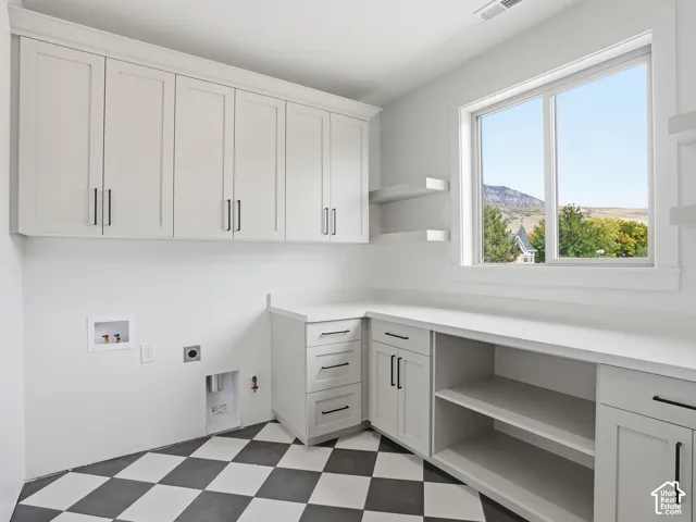 White shaker cabinetry, black and white checkered flooring, white countertops, built-in shelving, and a large window