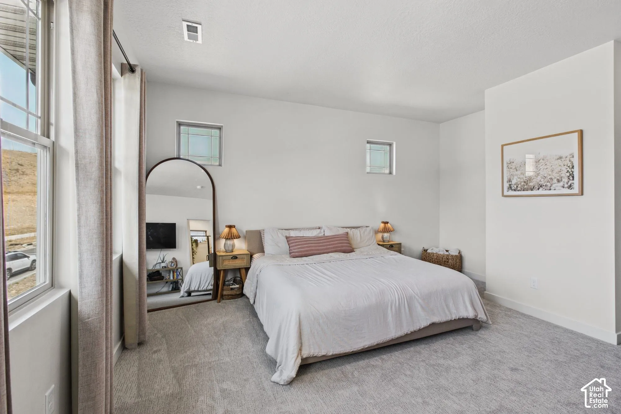 White painted walls, light gray carpeting, and multiple windows