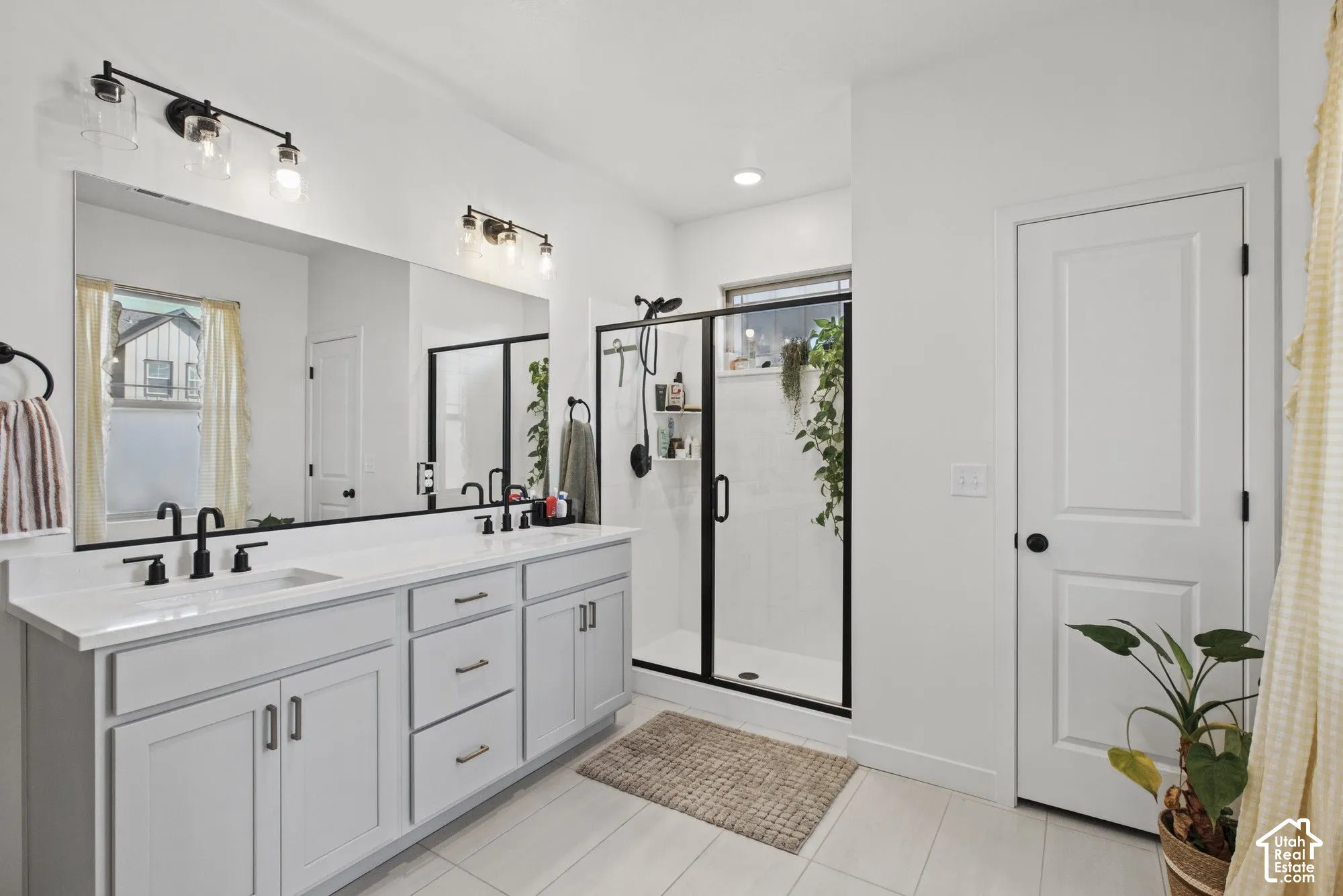 Dual vanity with white countertops, matte black faucets, and light-colored cabinetry