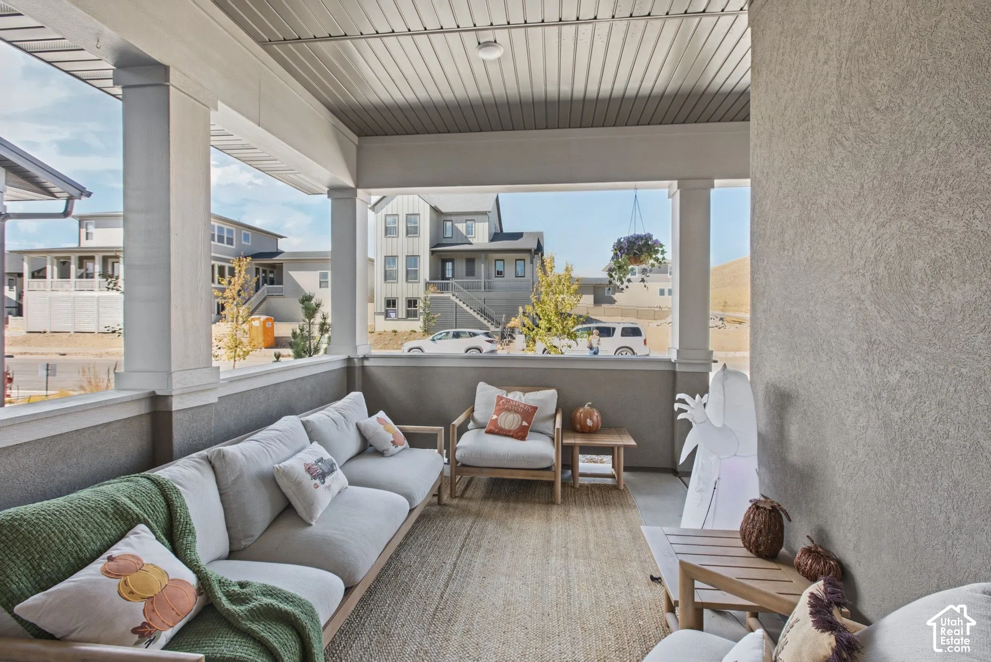 Covered porch with substantial columns, textured exterior wall finish, and a slatted ceiling