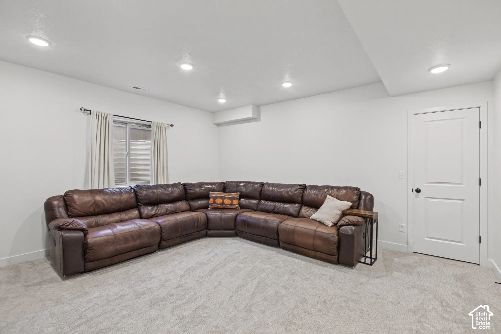 Recessed lighting illuminates the carpeted floor and white walls