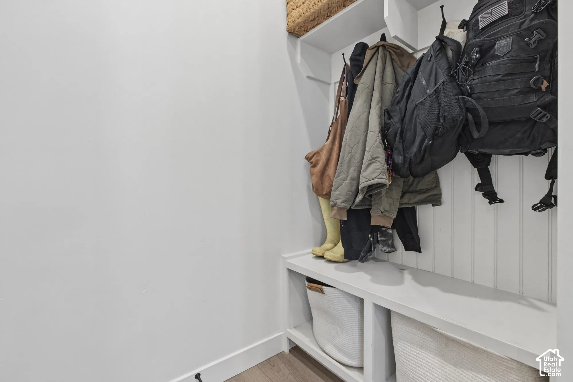 Built-in storage bench with overhead hooks, beadboard paneling, and upper shelving