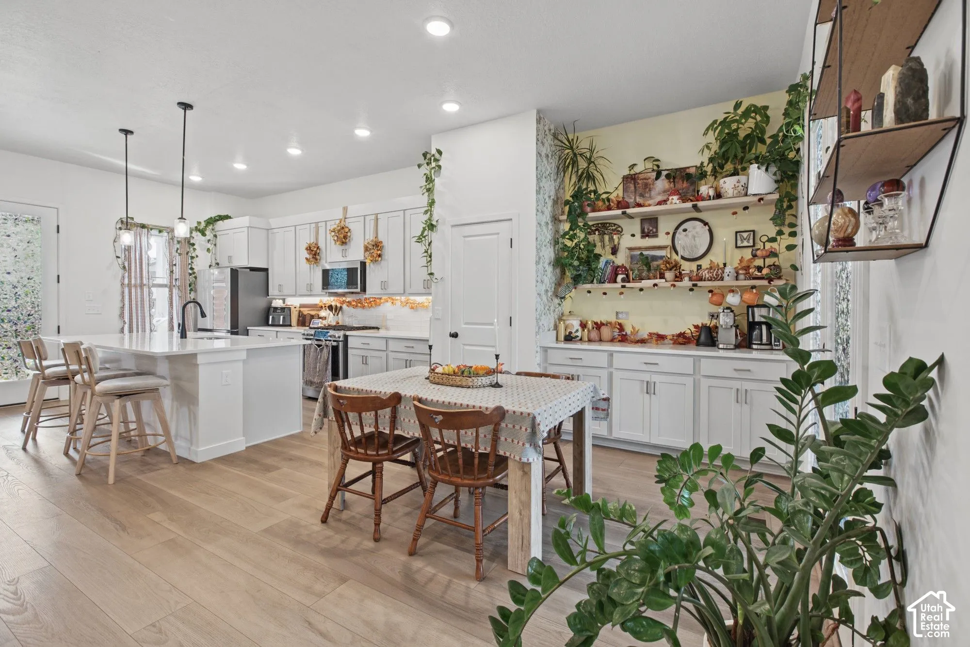 Open-concept kitchen featuring light wood-finish flooring, white cabinetry, a large island with seating, and recessed lighting