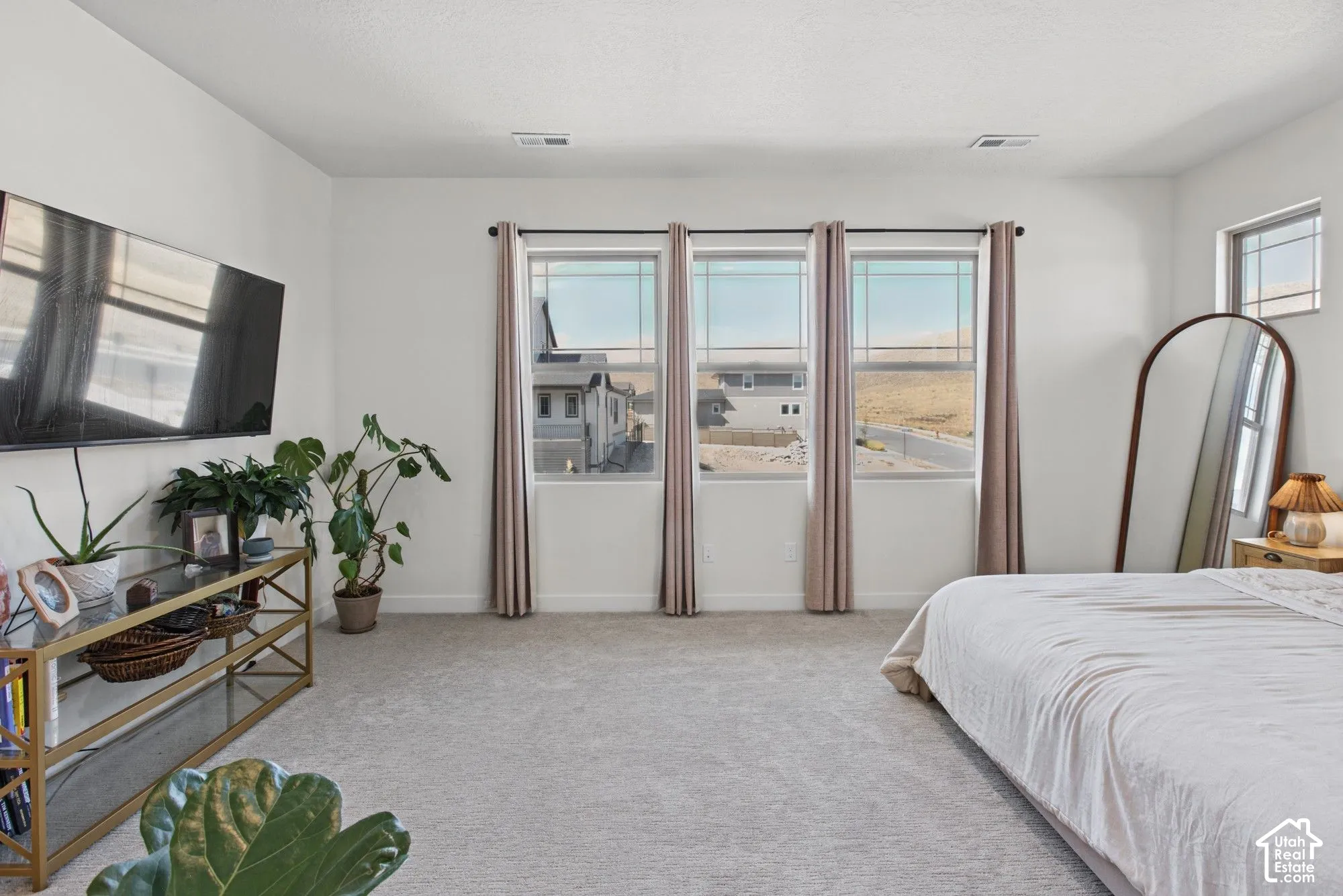 Recessed lighting, wall-mounted television, multiple windows, light-colored carpeting, and light-toned walls