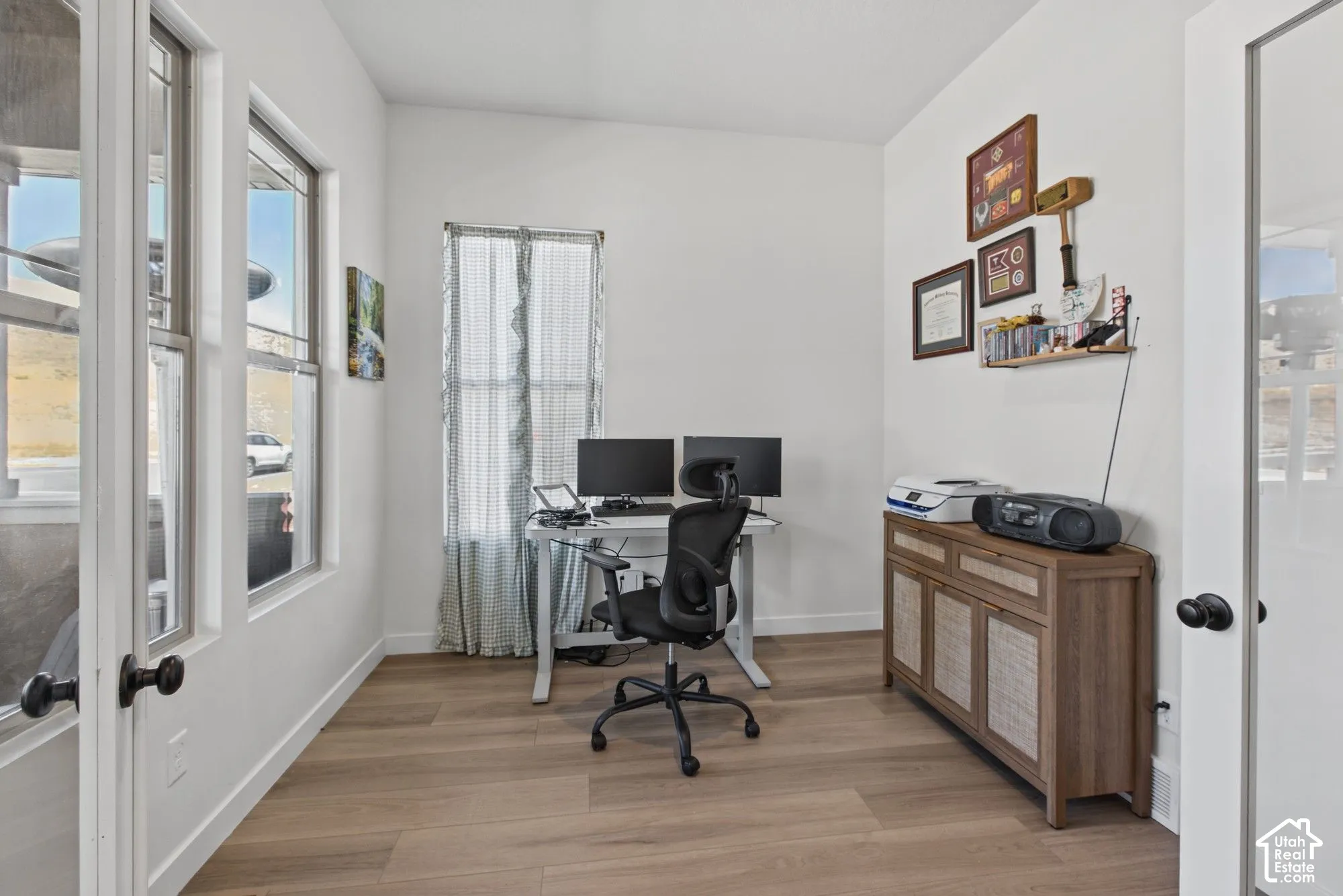 Bright interior with wood-finish flooring, white walls, and multiple windows allowing natural light