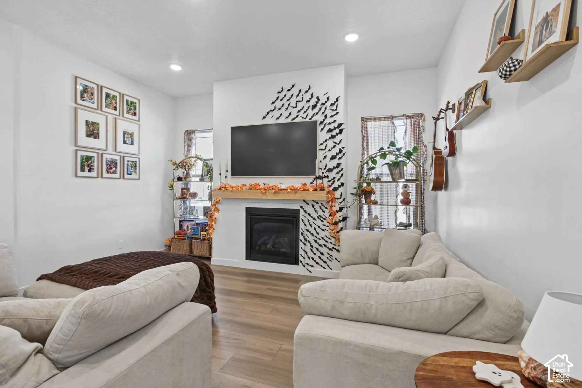 Recessed lighting illuminates the living area, featuring wood-finish flooring and a fireplace with a wood mantle