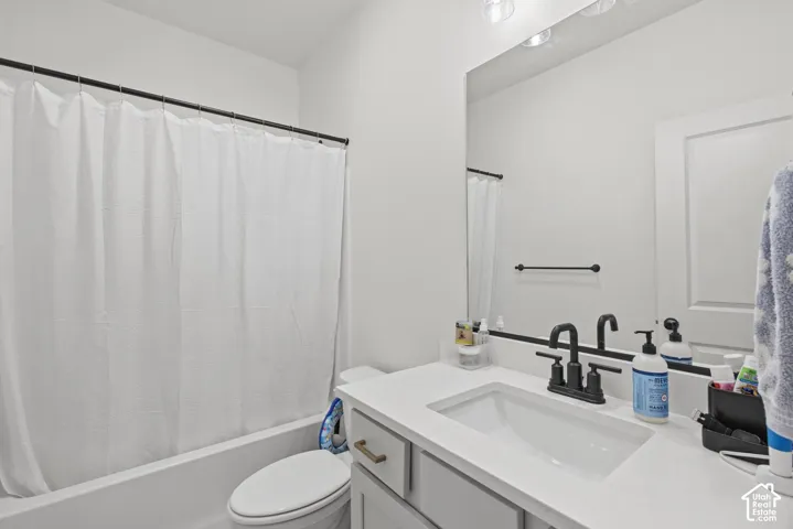 Bathroom featuring a white vanity with an integrated sink, black dual-handle faucet, and overhead lighting