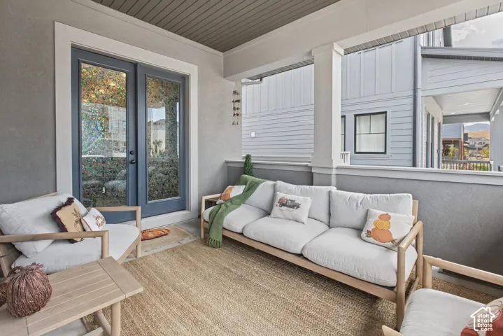 Covered patio featuring a textured wall finish, white columns, and a decorative French door entry