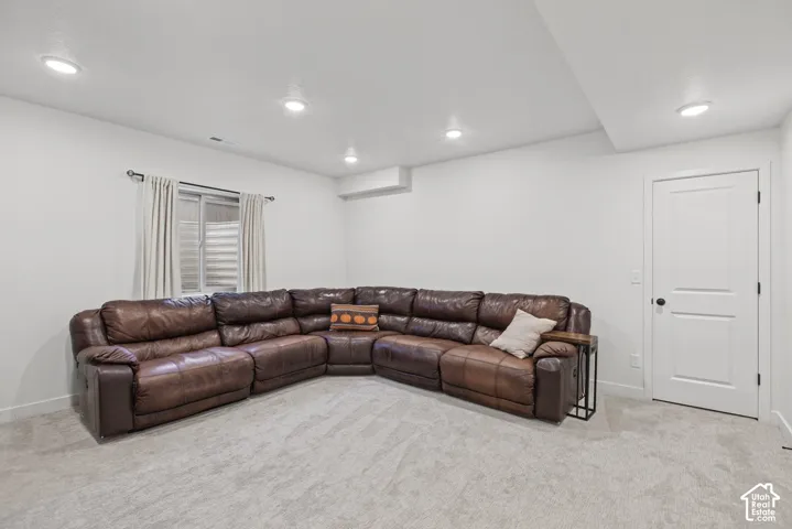 Recessed lighting illuminates the carpeted floor and white walls