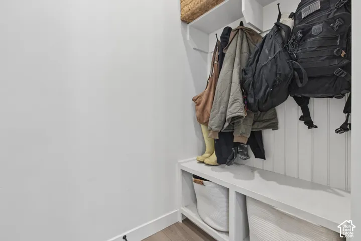 Built-in storage bench with overhead hooks, beadboard paneling, and upper shelving