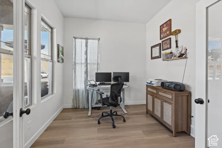 Bright interior with wood-finish flooring, white walls, and multiple windows allowing natural light