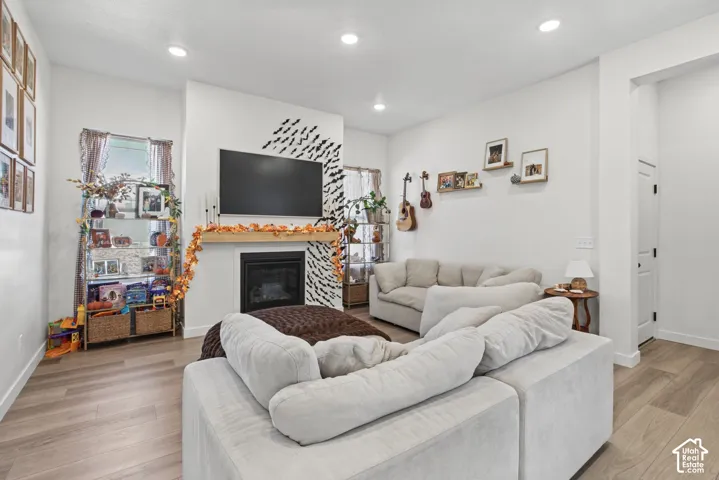 Recessed lighting, wood-finish flooring, and a fireplace with a wood mantle