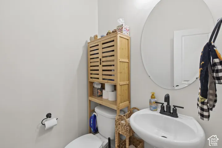 Wall-mounted sink with matte black faucet, oval mirror, and white wall finishes