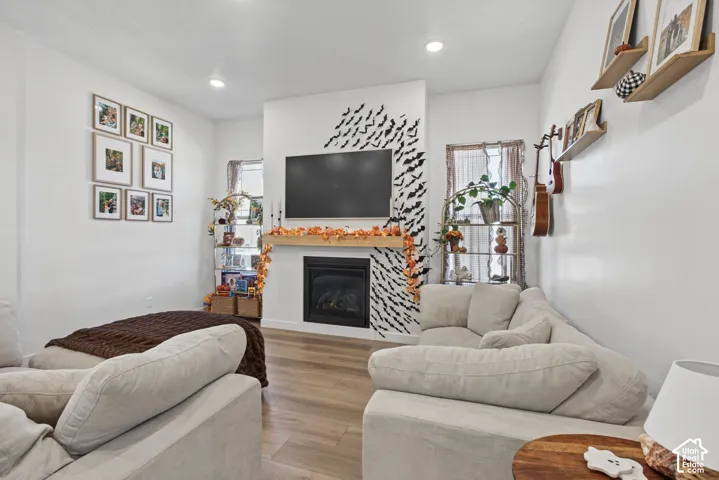 Recessed lighting illuminates the living area, featuring wood-finish flooring and a fireplace with a wood mantle