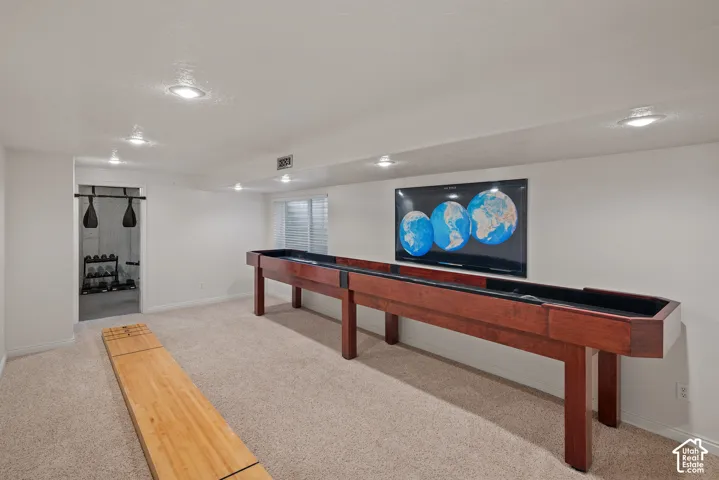 Recessed lighting, light-colored carpeting, and a window with horizontal blinds
